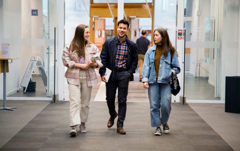 Tre studenter kommer ut från biblioteket.